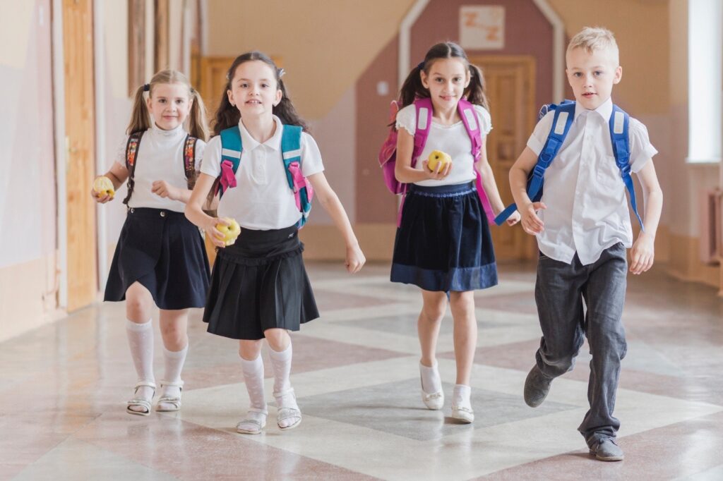 Elevi, copii cu ghiozdanele in spate la scoala / Foto: Freepik.com